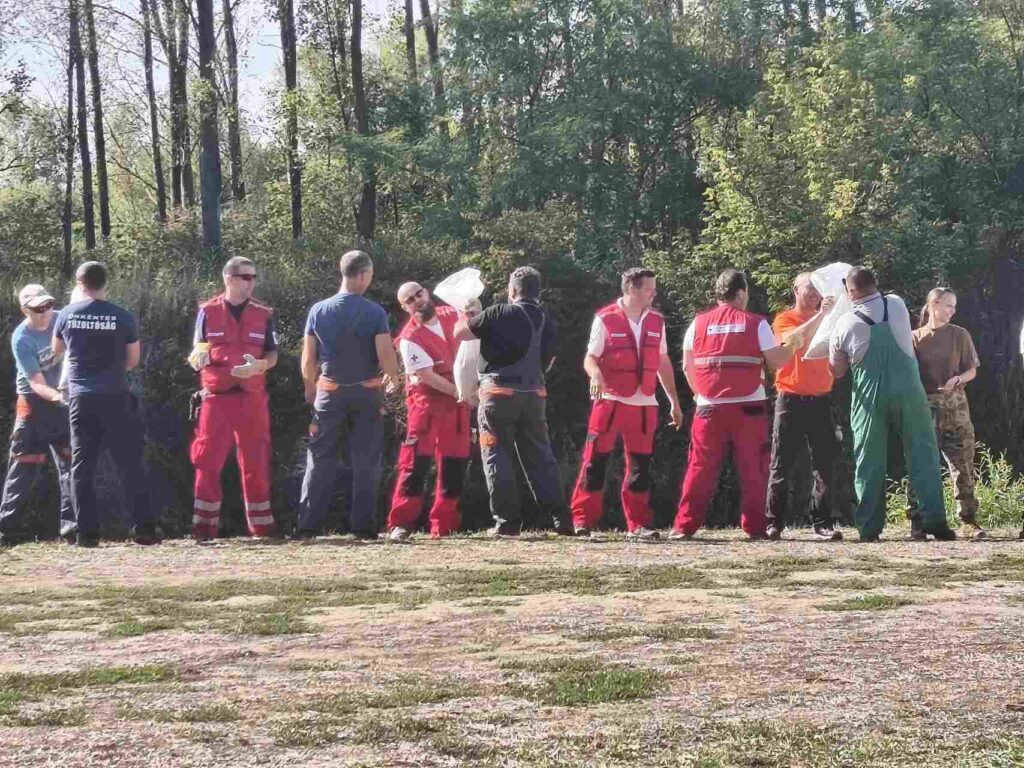Mentőcsoportok homokzsákot adogatnak láncban